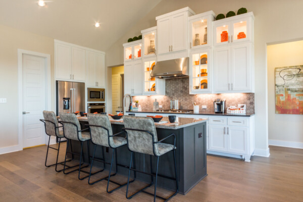 Kitchen with white perimeter cabinets with glass uppers, and and gray island cabinets