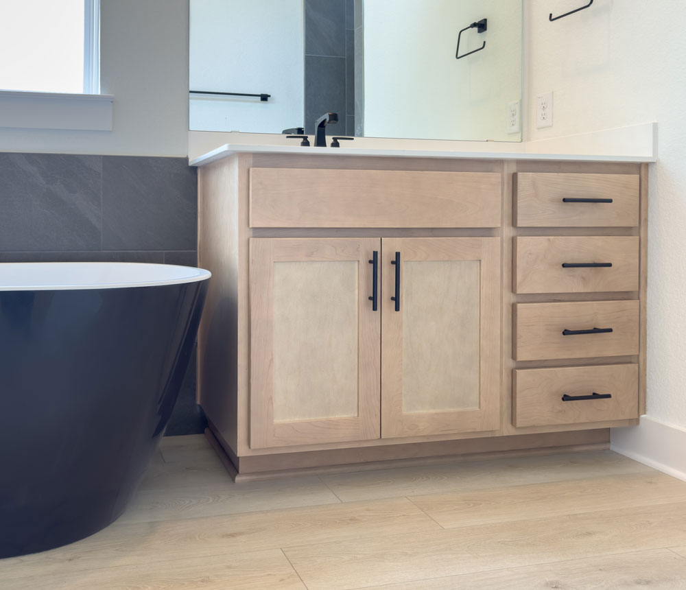 Maple bathroom cabinets with Shaker doors in OE4, IE2, flat panel with black soaking tub and wood floors