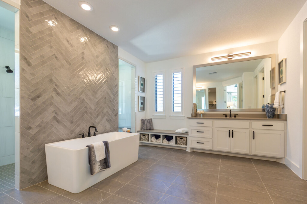 Warm modern bathroom with Shaker cabinet doors in OE4 IE2 and angular soaking tub with herringbone tile wall