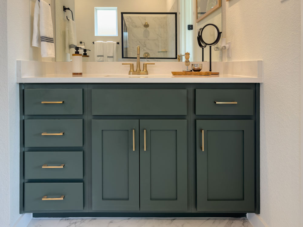 Bathroom vanity with Shaker cabinet doors in green paint with slab drawer fronts