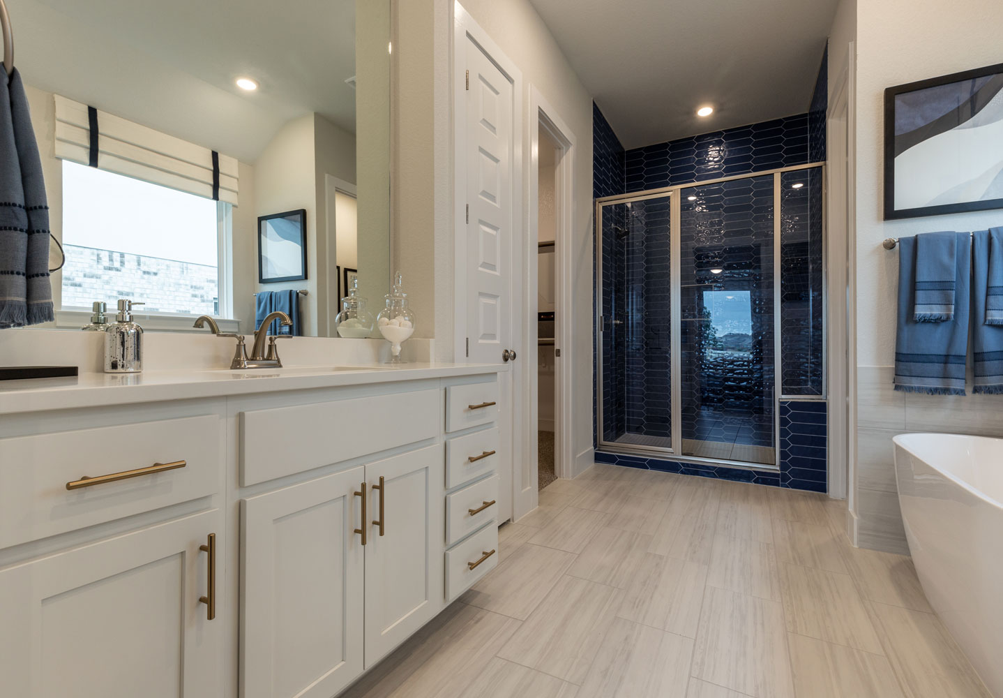 Bathroom with white Shaker cabinet doors and blue tile shower