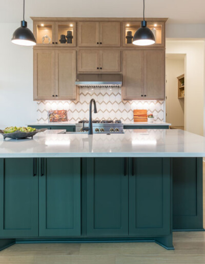Kitchen island with dark green paint paired with light, maple perimeter cabinets
