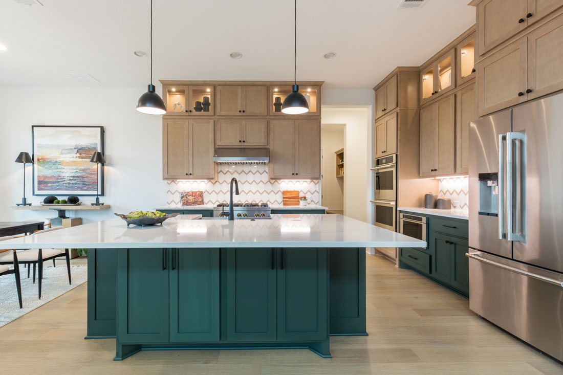 Kitchen island with dark green paint paired with light, maple perimeter cabinets and Shaker cabinet doors