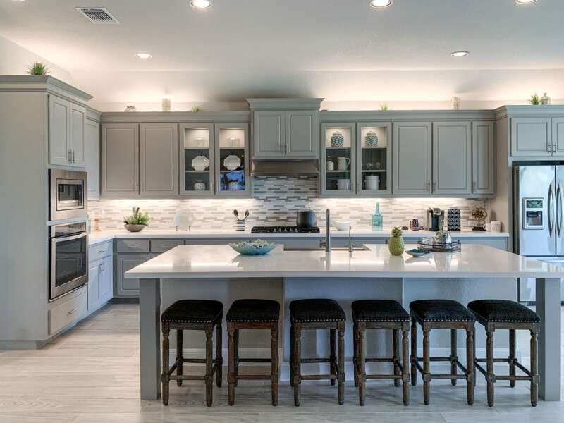 Kitchen with paint grade raised panel doors in light gray with large modern island with 6 bar stools