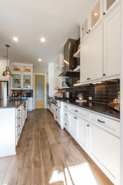 Kitchen with white shaker doors, black countertops, wood floors and yellow accent door