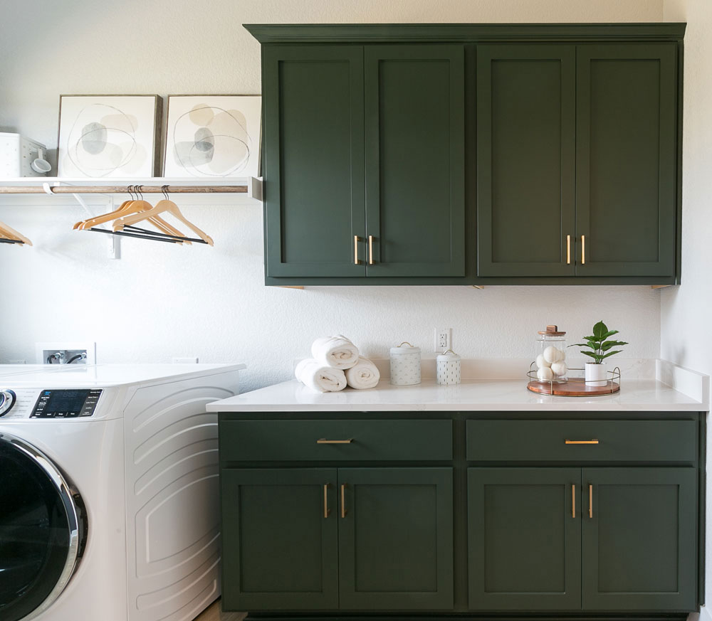 Green laundry room cabinets with Shaker cabinet doors in OE4, IE2, flat panel with gold pulls