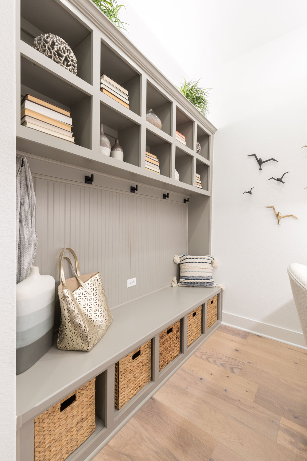 Built-in mud room cabinets with open shelves and upper and lower storage cubbies in gray paint